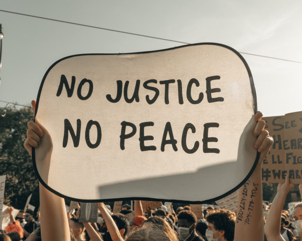 Protestor holding a sign saying "No Justice, No Peace"
