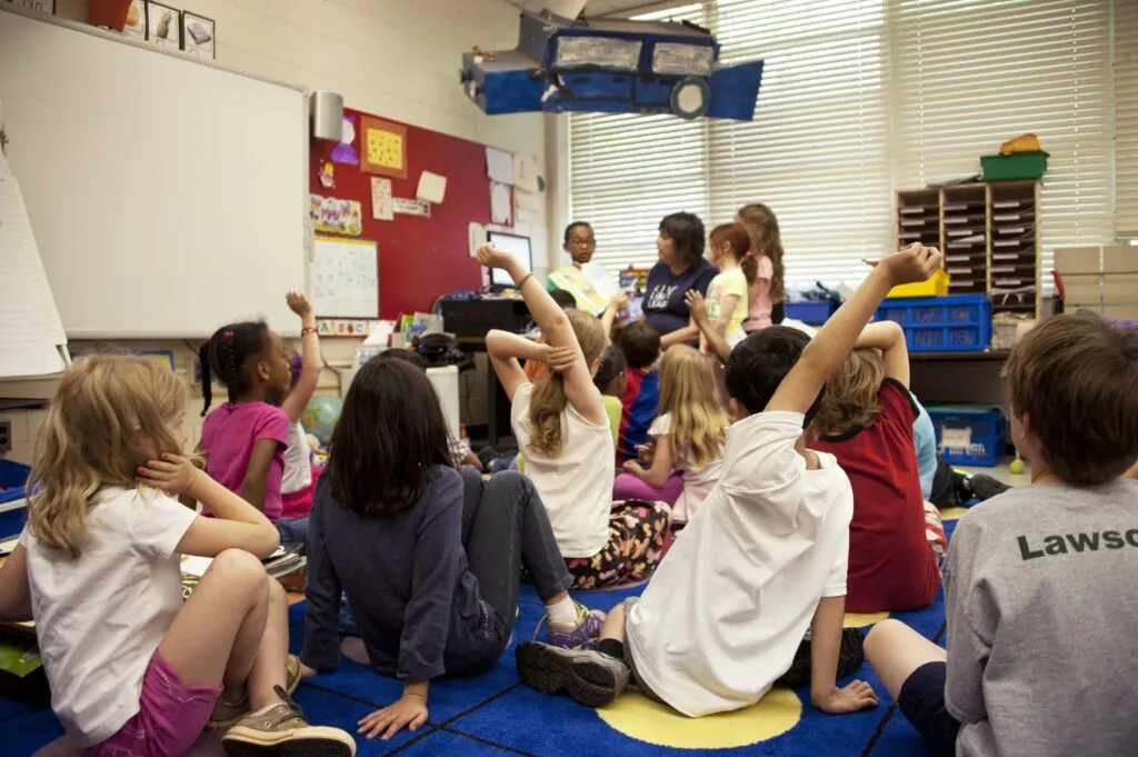 Classroom full of children of all genders and ethnicities sitting on the floor