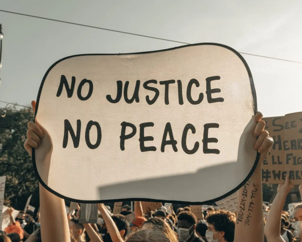 Protestor holding a sign saying "No Justice, No Peace"