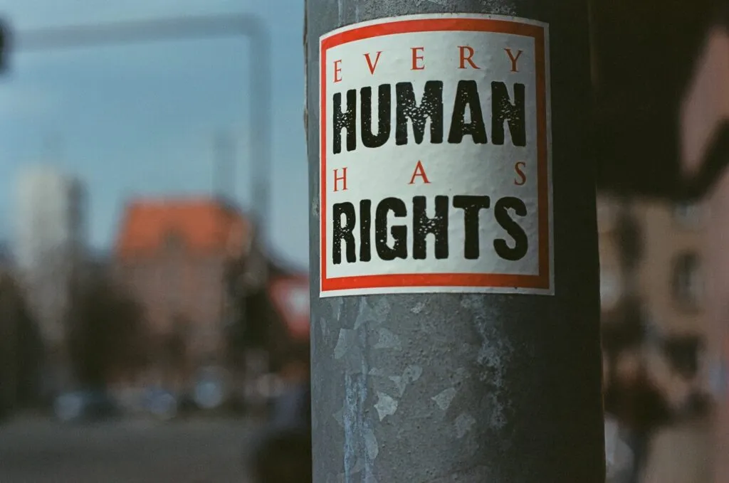The slogan "Every Human Has Rights" on a small square sticker stuck to a lamp post